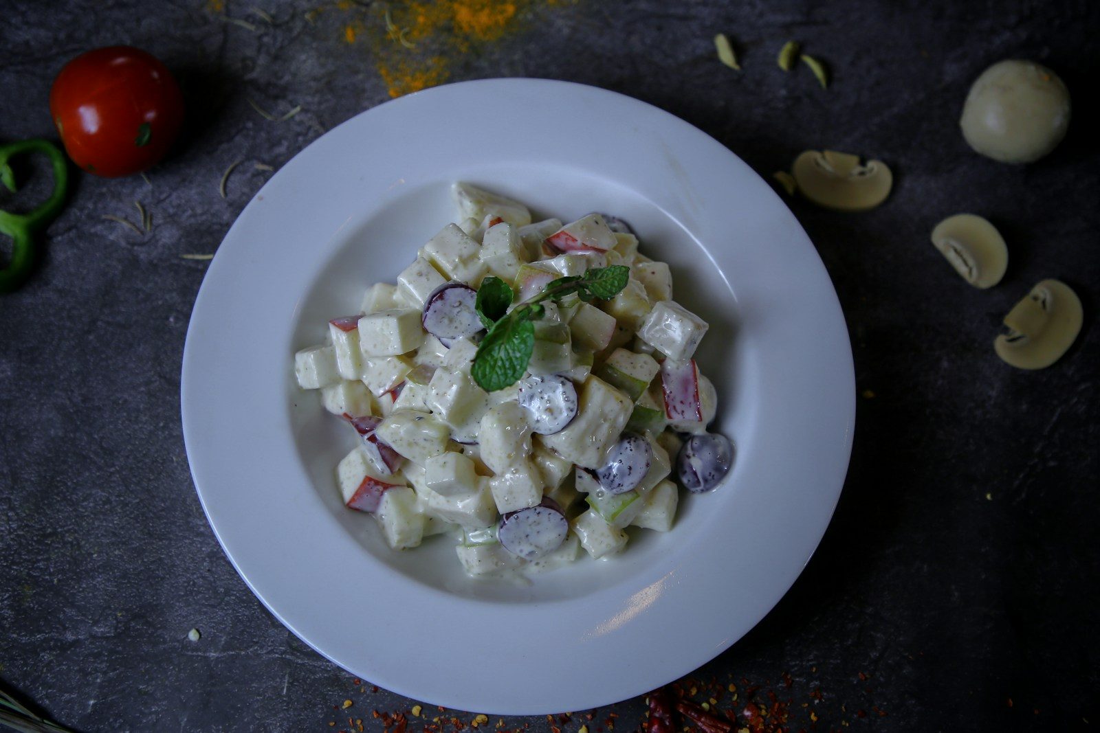 Creamy fruit salad with mint garnish on a plate