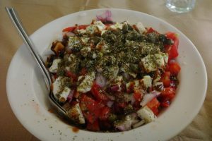 Photo by Teo Zac A bowl of salad with tomatoes, feta cheese, red onion, and herbs