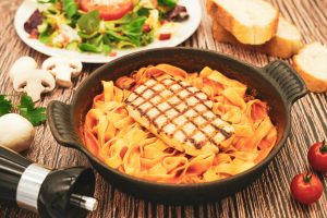 Photo by Arne Buss Grilled chicken pasta, fresh salad, bread, and wine on table