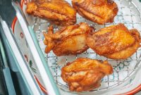 aap-air-fryer-chicken-thighs-with-crispy-skin-1791000870 Golden brown fried chicken pieces cooling on a wire rack, perfect for a delicious meal.