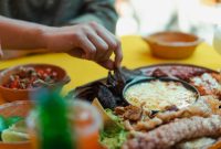 Hand reaching for delicious Mexican food platter, showcasing traditional dishes and vibrant colors.
