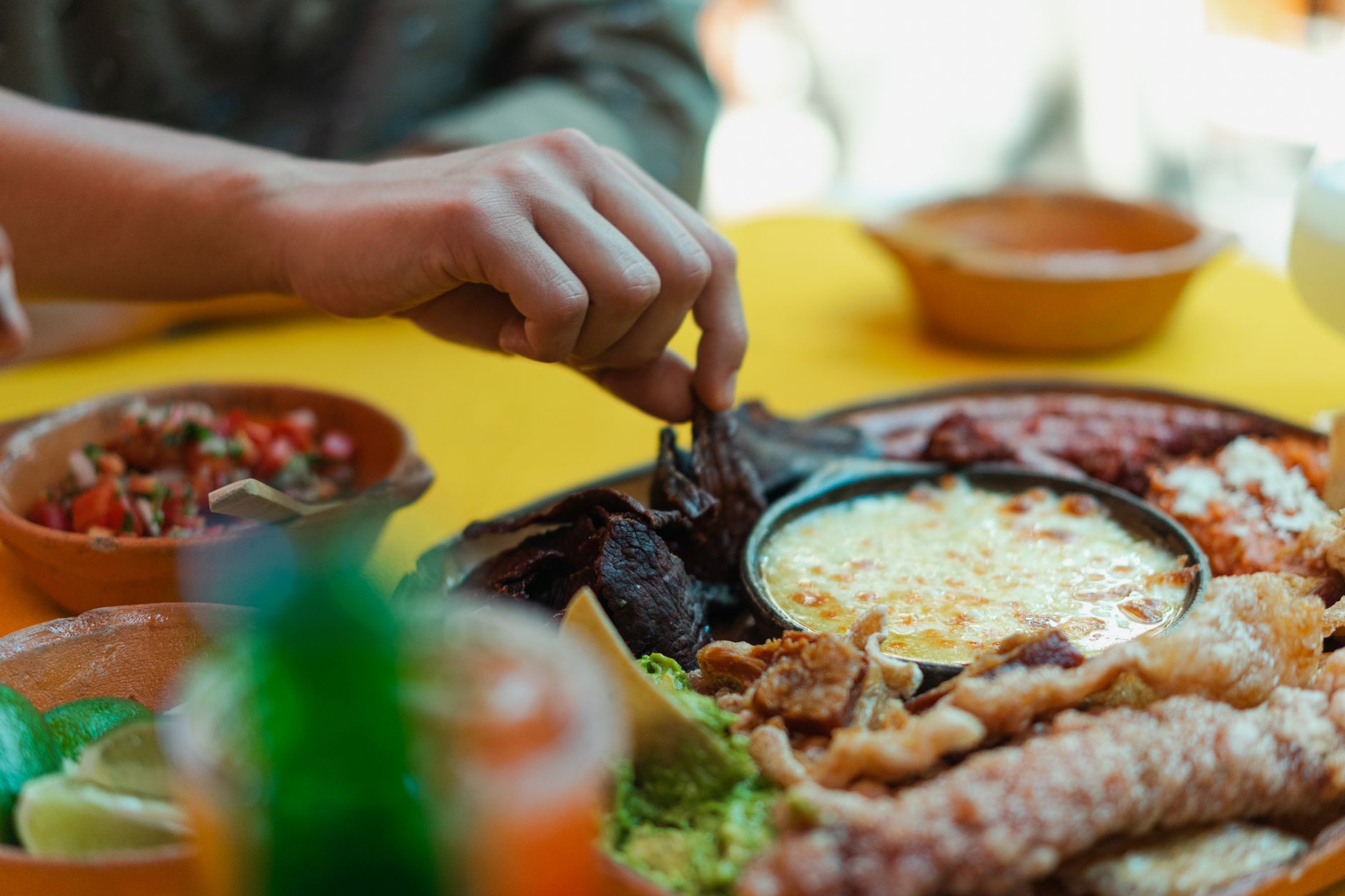Hand reaching for delicious Mexican food platter, showcasing traditional dishes and vibrant colors.