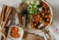 Delicious vegan bowl of chickpeas, rice, and cucumber, garnished with fresh herbs and spices.