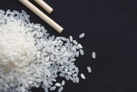 aap-japanese-home-cooking-recipes-for-beginners-1790850691 A close-up shot of raw rice grains with chopsticks on a black background, perfect for food and culinary themes.