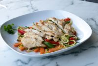 aap-low-carb-meal-prep-ideas-for-the-week-1790868418 Healthy grilled chicken breast served on zucchini noodles and fresh vegetables.