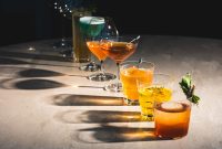 A colorful assortment of cocktails on a bar counter, showcasing diverse drink options.