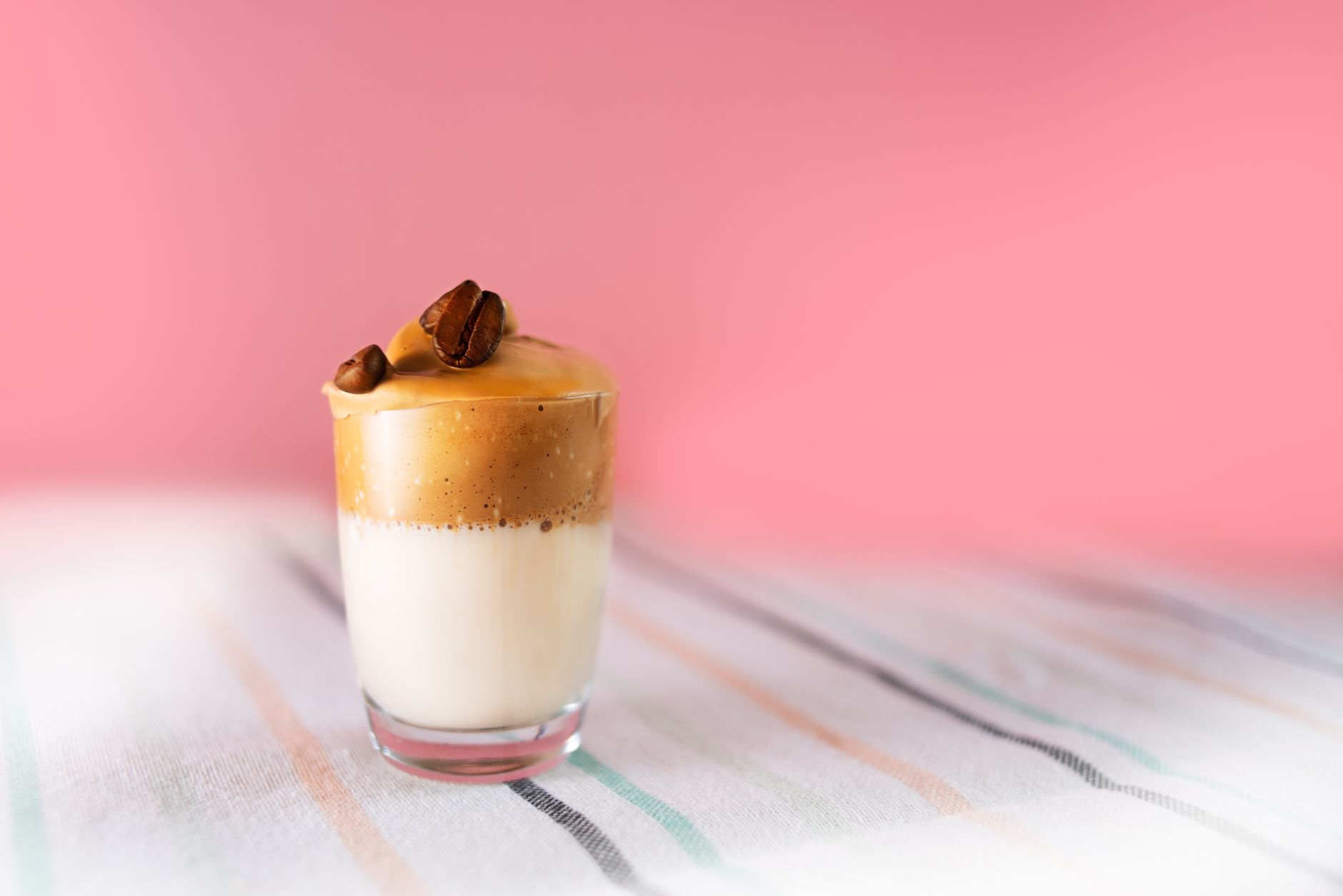 Aesthetic shot of dalgona coffee with creamy foam and topped with coffee beans.