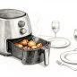Open Air Fryer Dinner An open air fryer holds chicken and vegetables beside two plates and wine glasses.